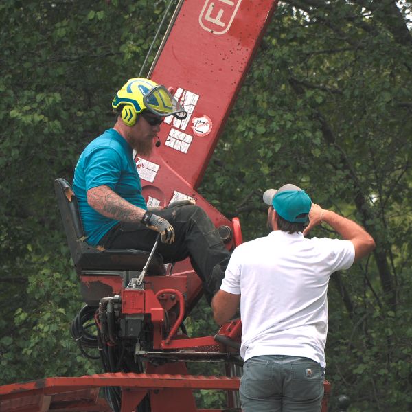 Website-arborist-services-section-arborist-talking Belgian Tree Service crew members engaged in conversation while one operates the grapple truck.